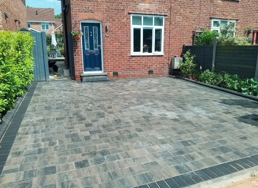 Mixed grey block paving outside a red-brick home