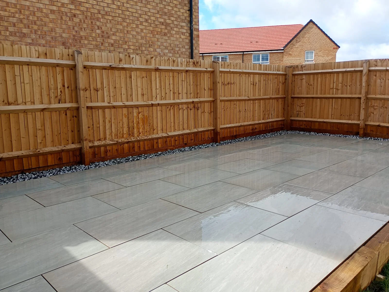Light grey patio paving beside new timber fencing