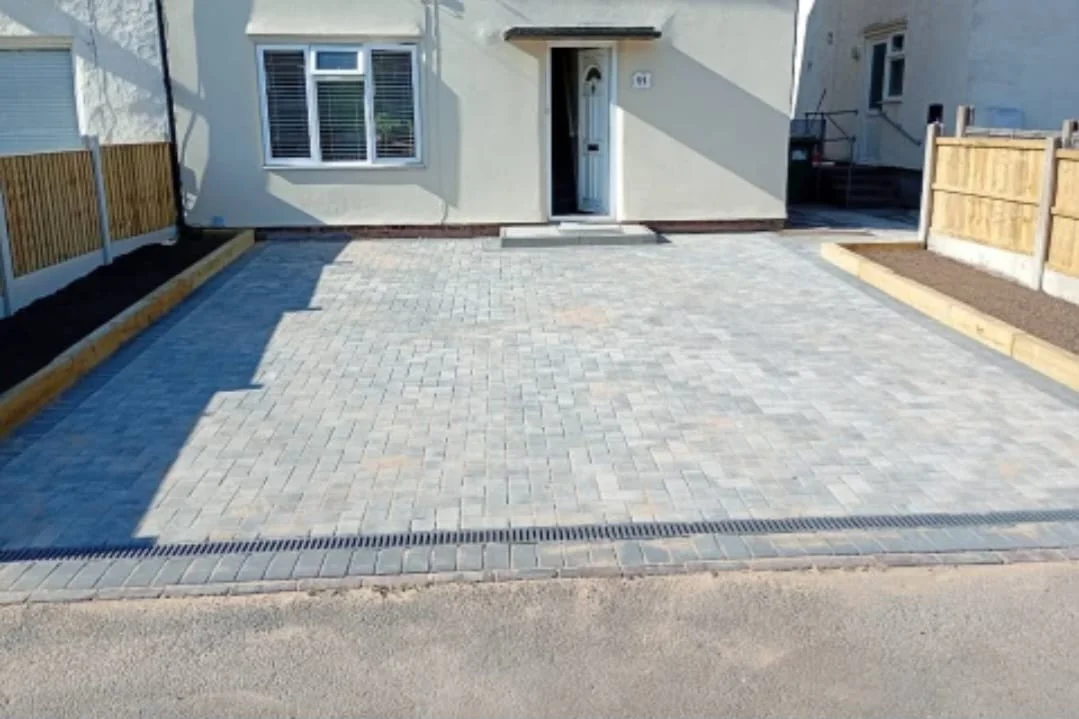 Grey block-paved driveway outside a white house