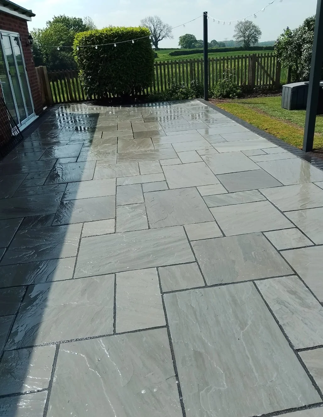 Stone paving and a path beside a house with an arched porch window — view 1