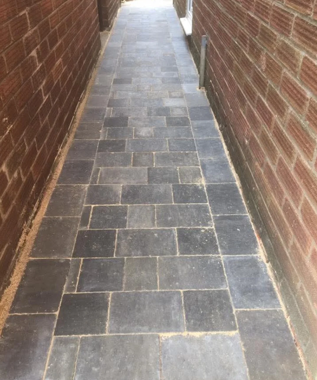 Block paving through a narrow brick-walled side passage — view 1