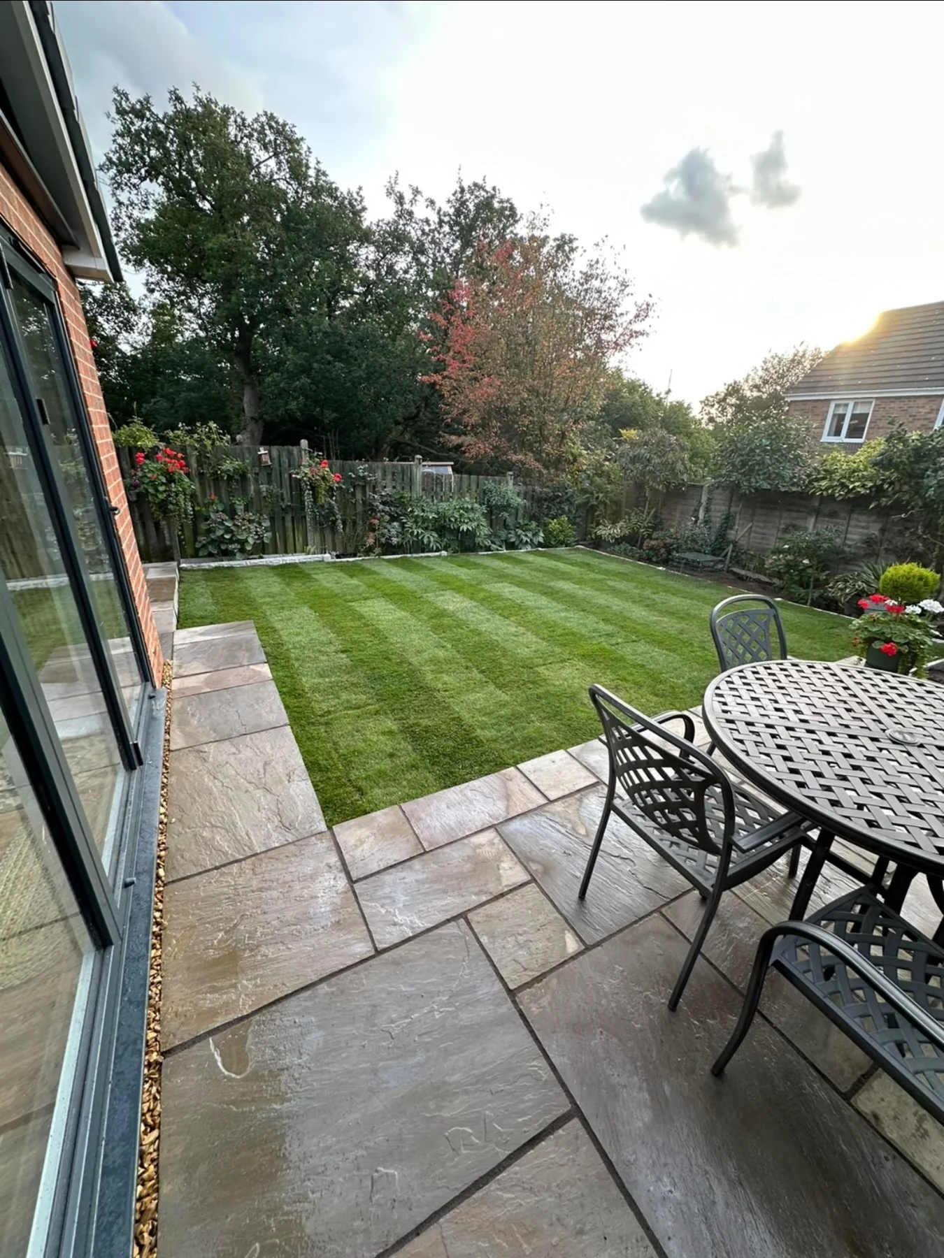 Striped lawn with a stone patio and garden seating — view 1